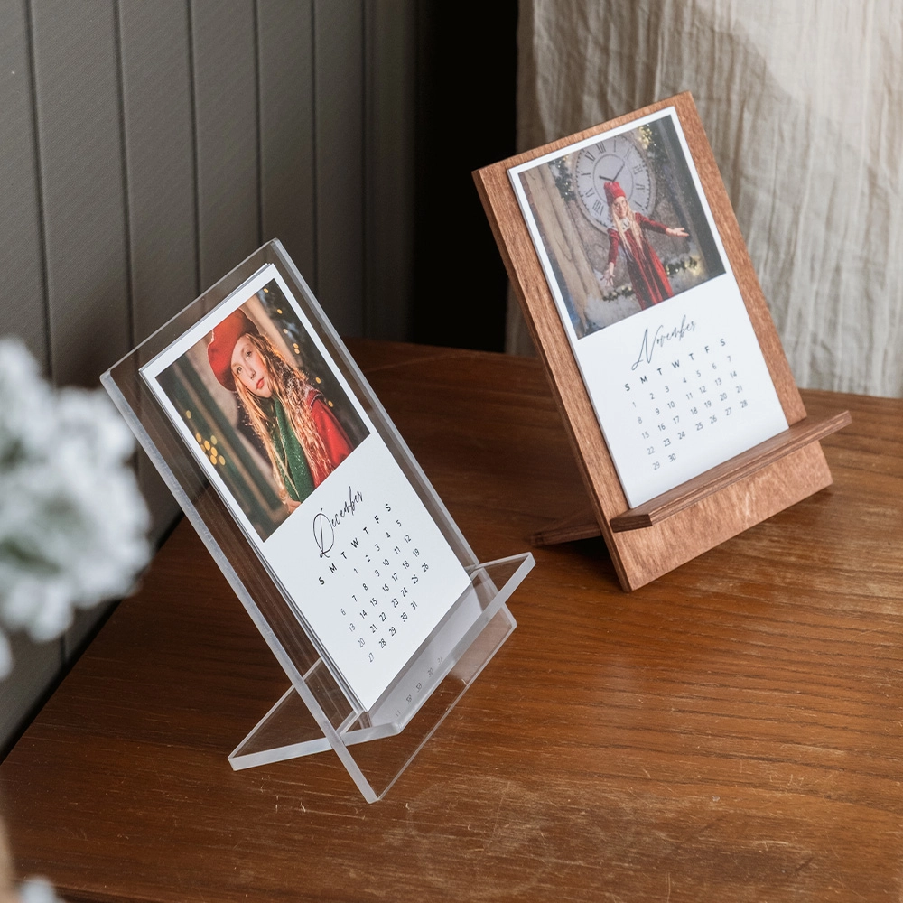 Calendario de escritorio personalizado con soporte de madera nogal o acrílico transparente. 6 hojas a doble cara con 12 fotos, papel True White Mate. Formato 10x15 cm. Regalo funcional y emotivo para clientes y espacios de trabajo.