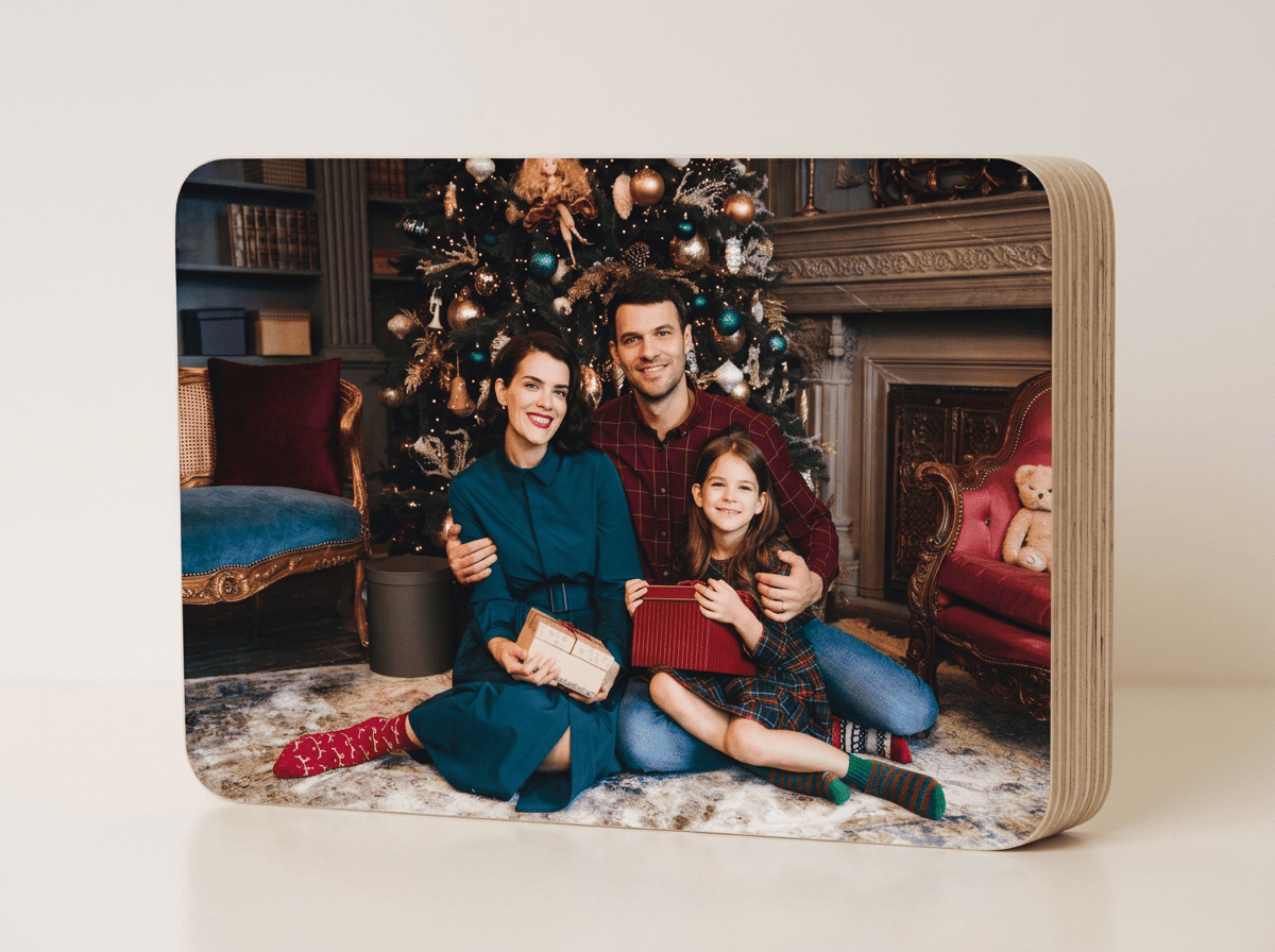 Taco ovalado personalizado de Navidad con fotografía familiar impresa, acabado mate y grosor de 19 mm, colocado sobre una mesa navideña con decoración de luces cálidas, ramas de pino, bolas rojas y lazos, destacando su diseño moderno y elegante como regalo y recuerdo navideño.